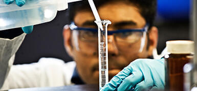 Student pouring liquid into a tube.